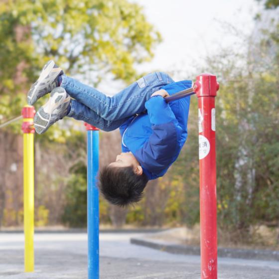 男の子が鉄棒で遊んでいる写真